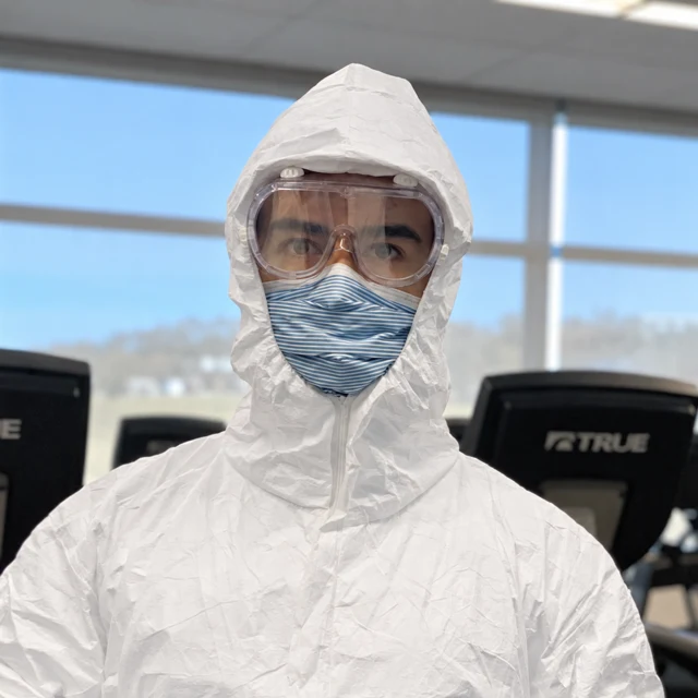 Julian Melo in a white protective suit, goggles and face mask